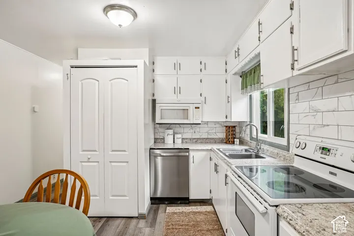 Kitchen featuring white cabinetry, light-toned countertops, a stainless steel dishwasher, and a tile backsplash