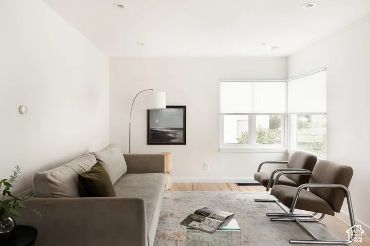 Recessed ceiling lighting, light wood-finish flooring, and corner windows with roller shades