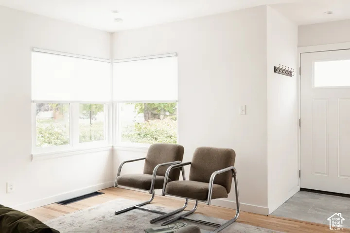 Corner windows with roller shades, recessed lighting, and wood-finish flooring