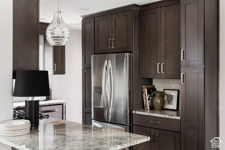 Stainless steel refrigerator, extensive dark wood-finish cabinetry, light-toned granite countertops, and a white subway tile backsplash