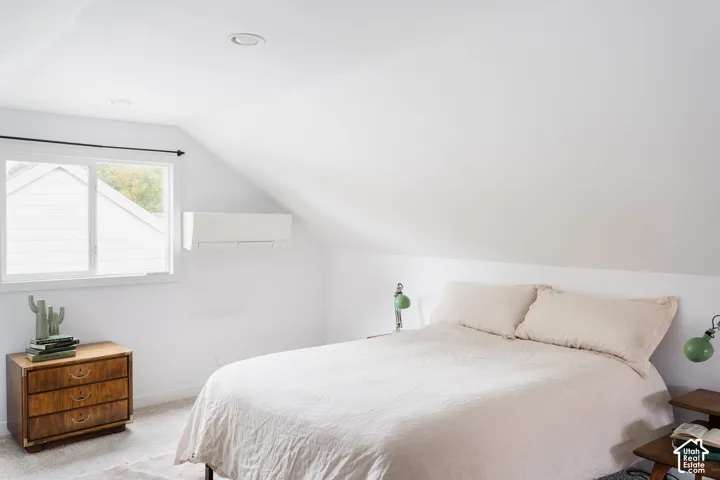 Sloped ceiling with recessed lighting, single window, and a wall-mounted climate control unit