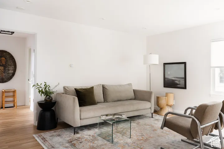 Light wood-finish flooring, recessed ceiling lighting, a white window blind, and a doorway