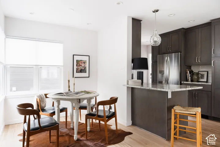 Recessed lighting, wood-finish flooring, white walls, dark cabinetry, and a light-colored countertop