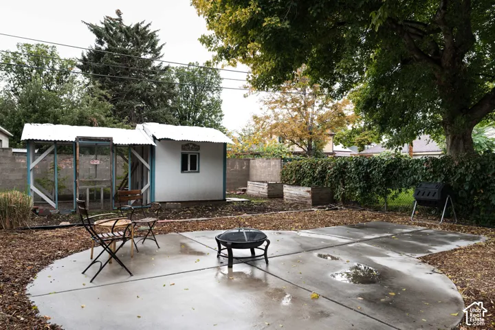 Curved concrete patio with a fire pit, bordered by natural mulch