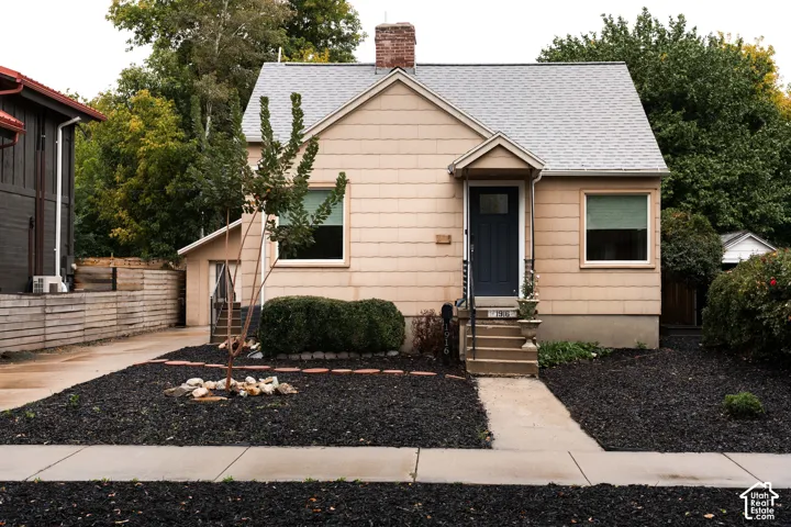 Siding exterior with a covered entry, stone steps, a dark-toned front door, and a paved driveway