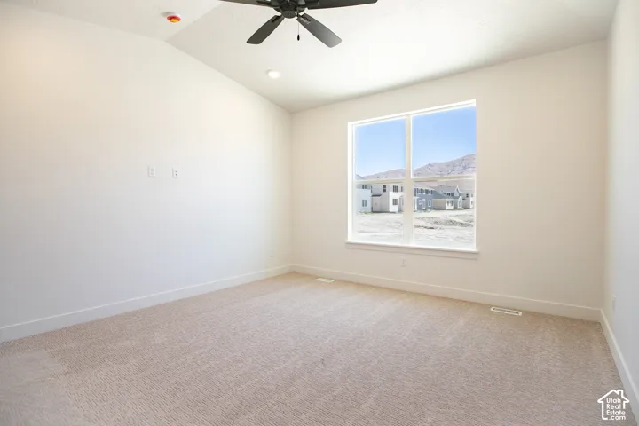 Primary bedroom with vaulted ceiling and ceiling fan.