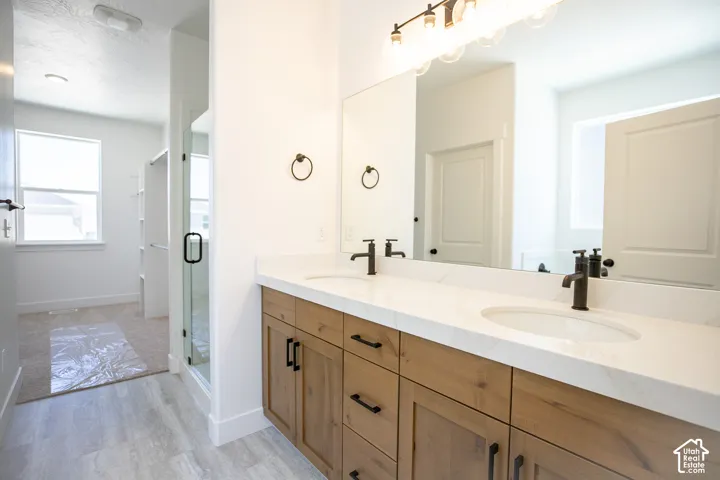 Primary bath with dual sinks, stained wood cabinets and quartz slab countertops.