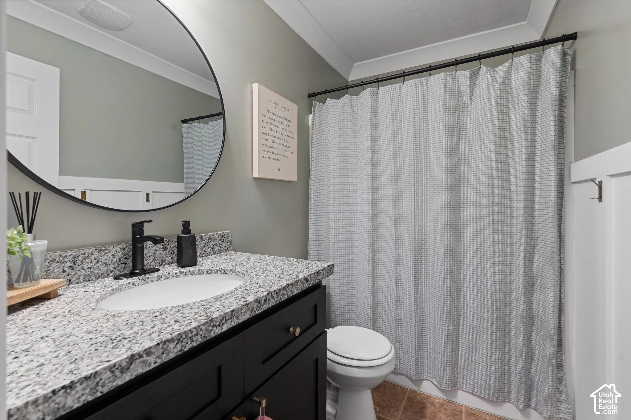 Bathroom vanity with a dark wood-finish cabinet and a speckled stone countertop