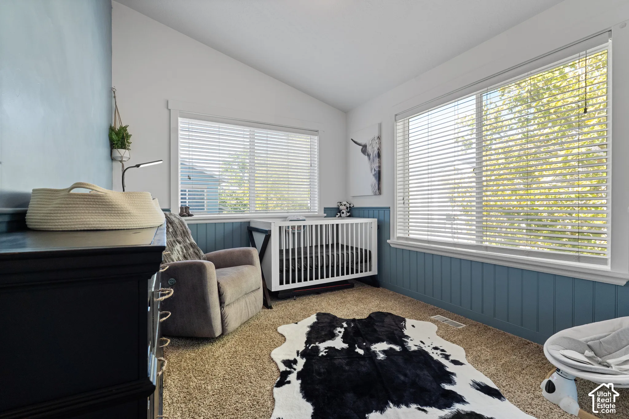Vaulted ceiling with white paint, light blue accent wall, white window frames, and light brown carpet flooring