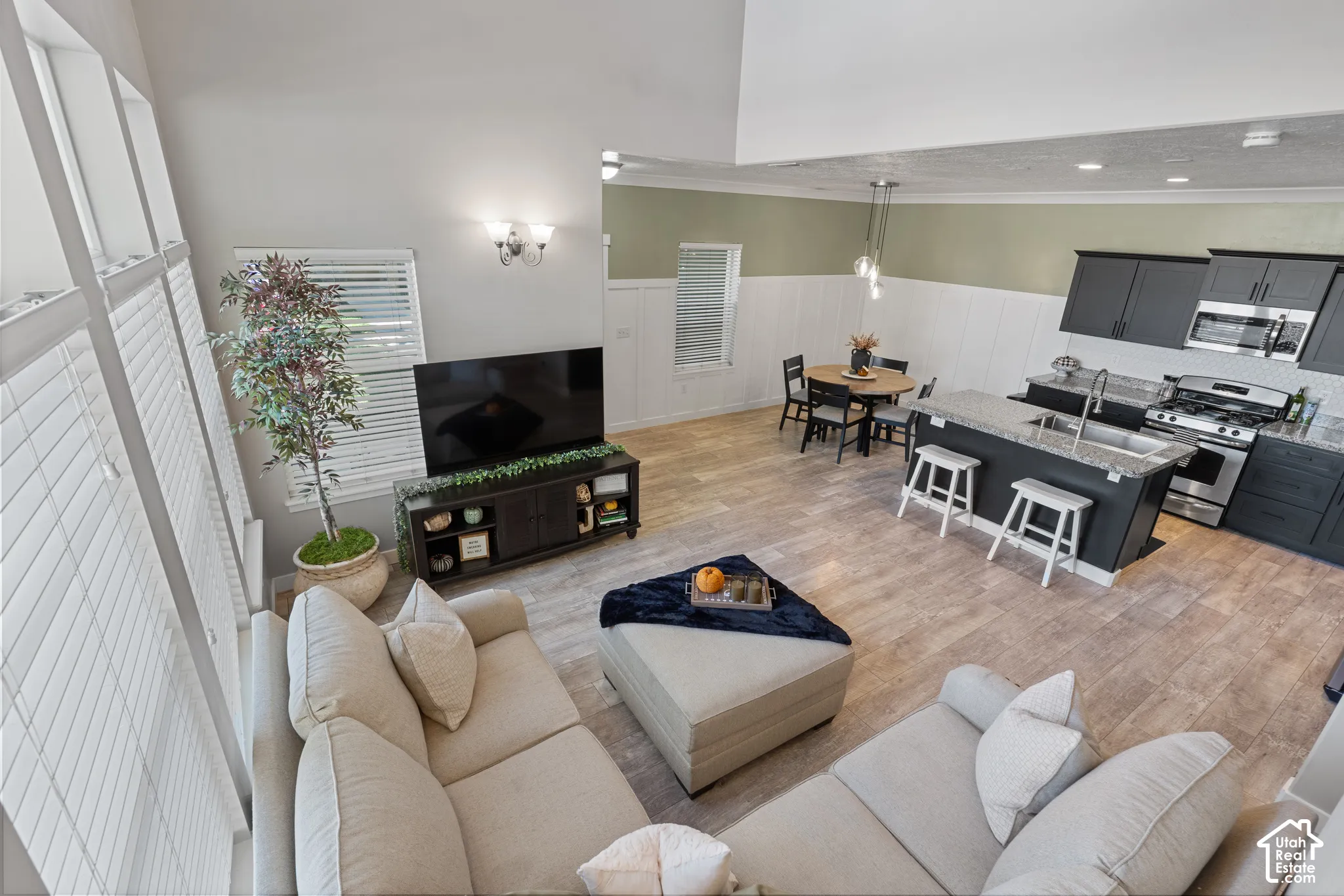 Vaulted ceiling, wood-finish flooring, dark cabinetry, stainless steel appliances, and kitchen island with seating
