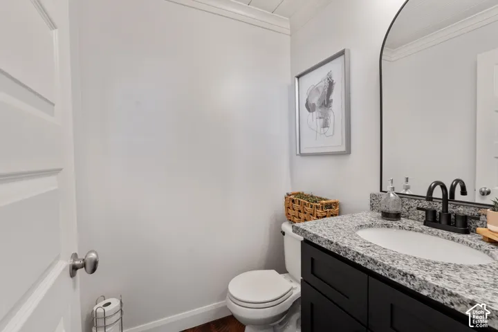 Granite countertop vanity with integrated sink, black cabinetry, matte black faucet, and arched mirror