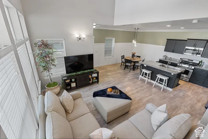 Vaulted ceiling, wood-finish flooring, dark cabinetry, stainless steel appliances, and kitchen island with seating