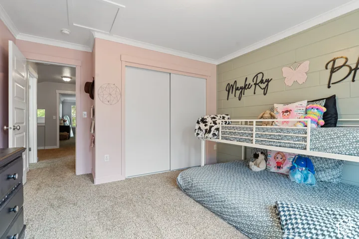 Bright secondary bedroom featuring soft pink accent walls, white sliding closet doors with ample storage, neutral carpeting, and decorative wall decals