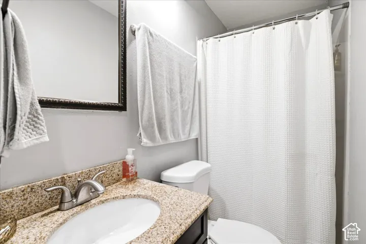 Bathroom featuring a vanity with a granite-style countertop, undermount sink, and a framed wall mirror