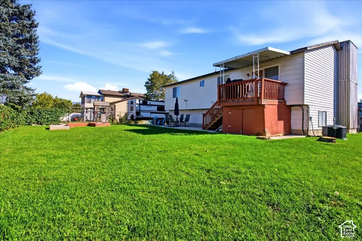 Expansive green lawn with a privacy hedge, raised garden beds, and a wood deck