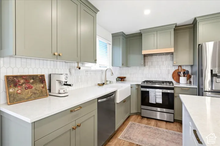 Kitchen featuring sage cabinetry, white quartz countertops, a white farmhouse sink, and stainless steel appliances