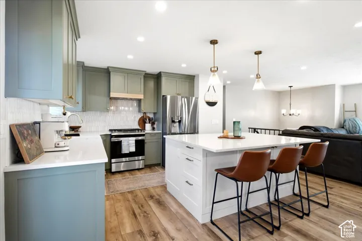 Kitchen featuring two-tone cabinetry, stainless steel appliances, a white tile backsplash, and a central island with a white countertop
