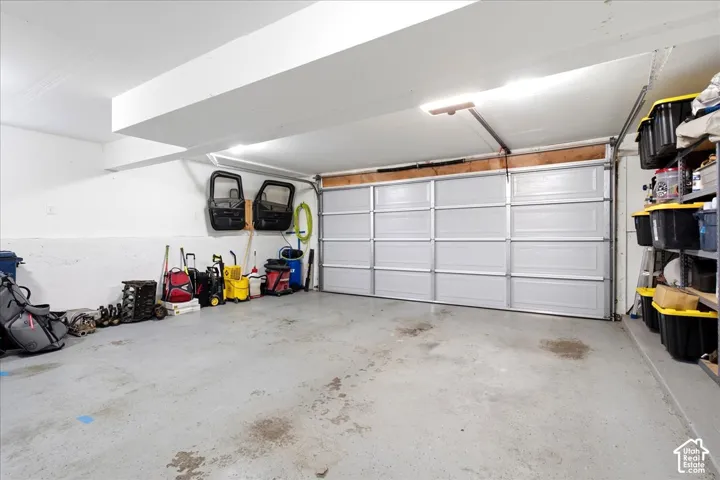 Spacious garage with a sectional overhead door, concrete flooring, and overhead lighting