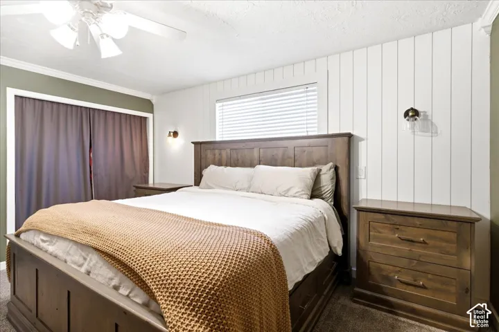 White shiplap accent wall, wall-mounted sconces, and a ceiling fan with integrated lighting