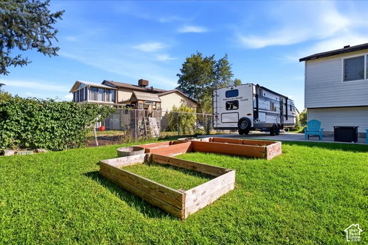 Expansive backyard featuring a green lawn, two raised garden beds, and a paved area