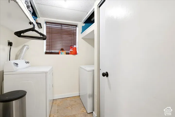 Dedicated laundry space featuring a window with blinds, overhead shelving, and tile flooring