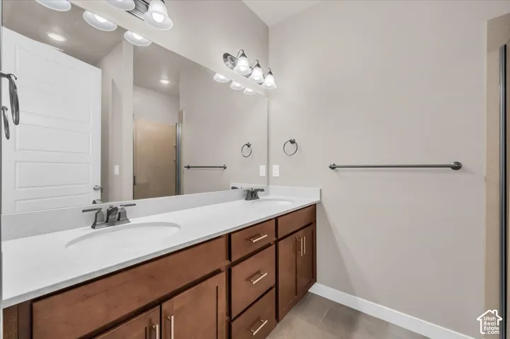 Dual vanity with white undermount sinks, stone-finish countertop, and wood-finish cabinetry