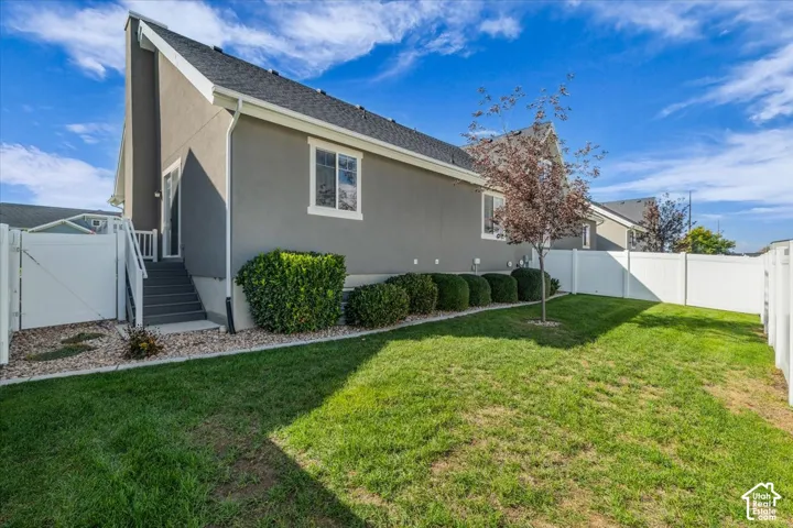 Landscaped backyard featuring a manicured lawn, established shrubbery, and a young deciduous tree
