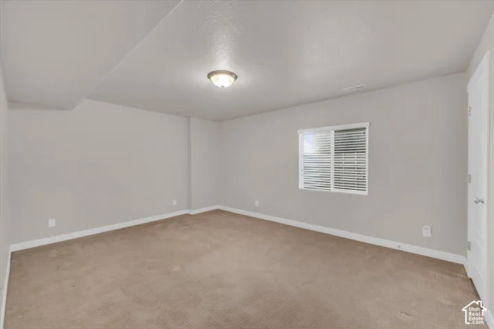 Recessed lighting, neutral wall paint, window with blinds, light-colored carpet flooring, white interior door