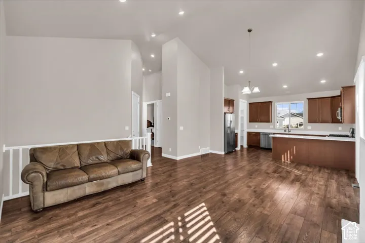 Open-concept living and kitchen area featuring rich wood-finish flooring, recessed ceiling lighting, and stainless steel appliances