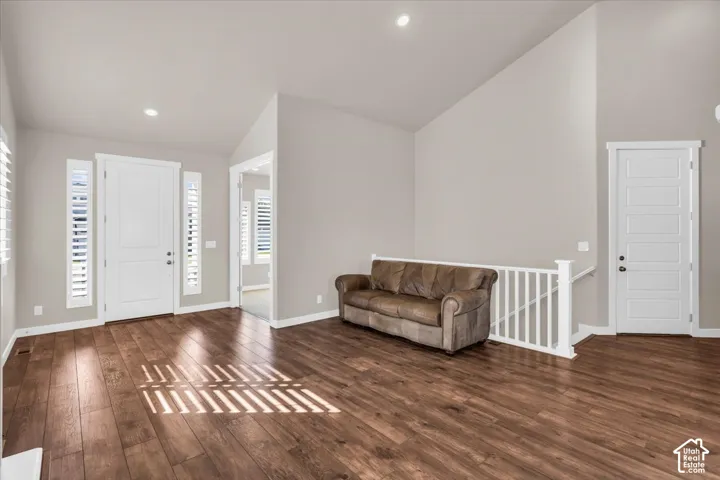 Vaulted ceilings with recessed lighting, wood-finish flooring, white panel doors, and white plantation shutters