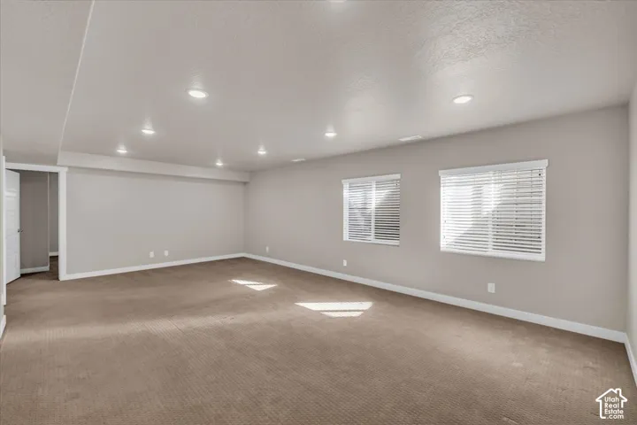 Recessed lighting, two windows with blinds, light-toned wall paint, and neutral-toned carpet flooring