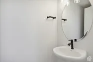 Pedestal sink with a matte black faucet, wall-mounted oval mirror, and contemporary light fixture
