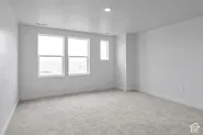 Neutral-toned interior space featuring wall-to-wall carpeting, recessed ceiling lighting, and multiple windows