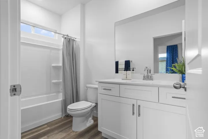 White vanity with shaker-style cabinetry, chrome fixtures, integrated sink, and wood-finish flooring