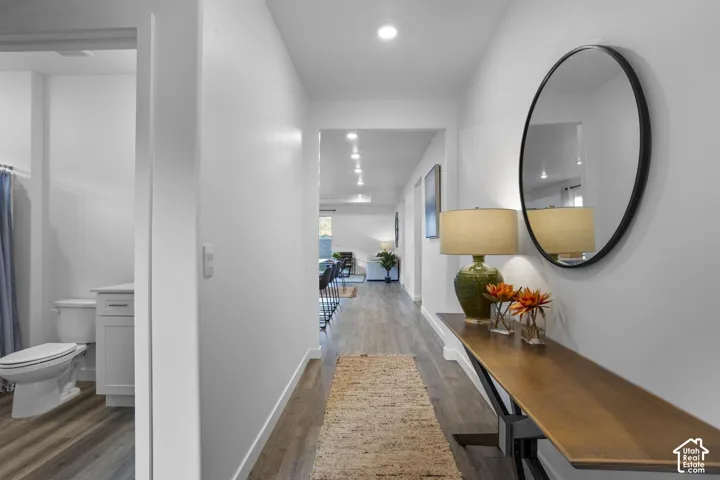 Recessed ceiling lighting illuminates the hallway with wood-finish flooring
