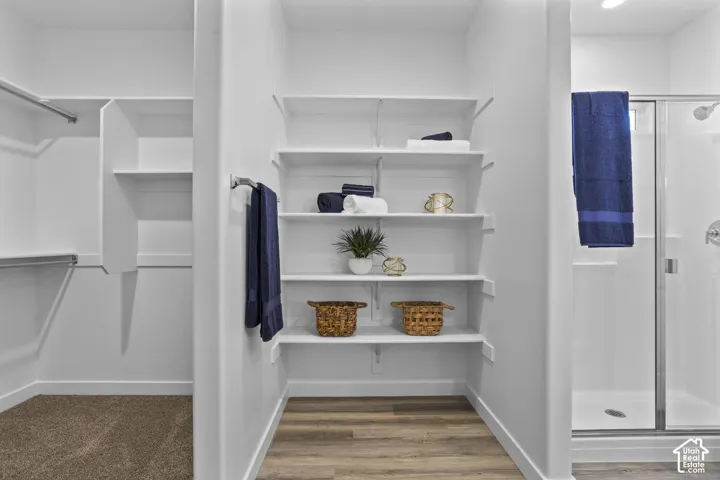 Built-in shelving, wood-finish flooring, recessed lighting, chrome towel bar, and glass-enclosed shower
