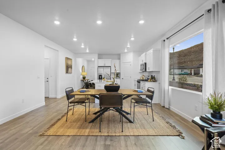 Open-concept living area with wood-finish flooring, recessed lighting, and a prominent window