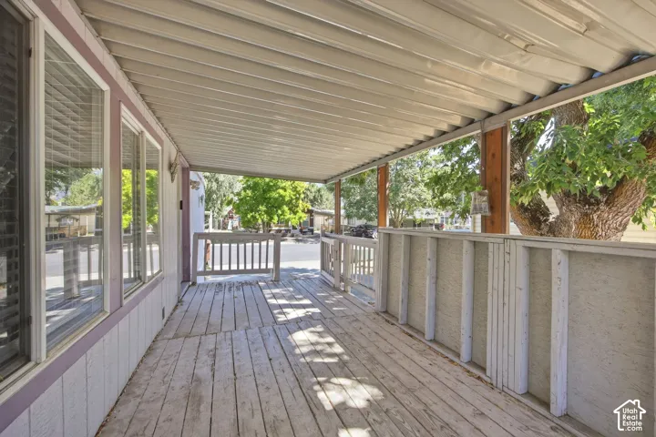Covered wood-finish porch featuring white railing and support beams