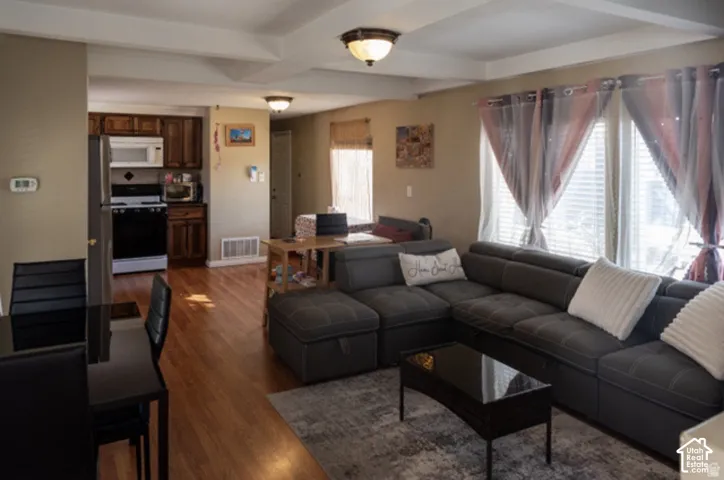Open-concept living area with hardwood flooring, recessed ceiling details, and multiple windows