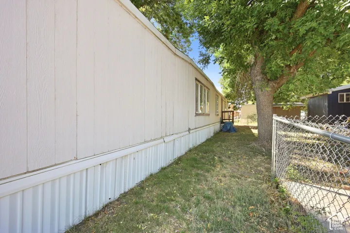 Light-colored vertical siding with white foundation skirting, featuring multiple windows