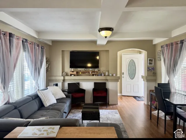 Wood-finish flooring throughout, recessed ceiling beams, and arched entryway