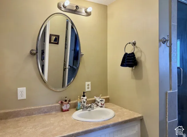 Elegant bathroom vanity featuring a round tilting mirror with brushed nickel frame, circular undermount sink, and stone-finish countertop