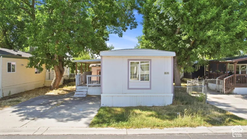White exterior with purple trim, featuring a covered porch, wood-finish steps, and mature trees