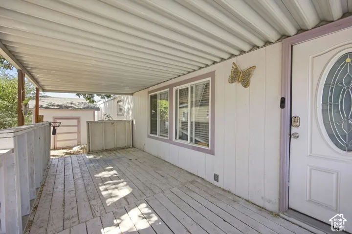 Covered porch with wood-finish decking, white siding, and an ornate front entry door with an oval glass insert