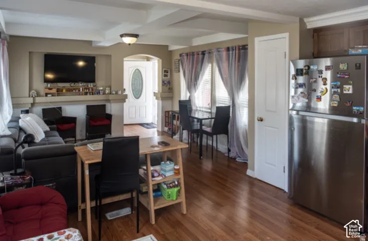 Wood-finish flooring throughout, stainless steel refrigerator, recessed media niche with decorative mantel, coffered ceiling detail, and an oval-paneled entry door