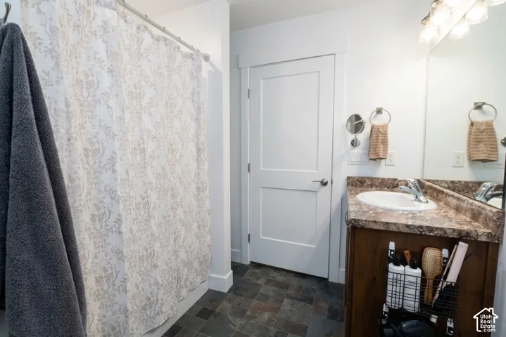 Bathroom featuring a wood-finish vanity with a built-in sink, a large mirror, and overhead lighting