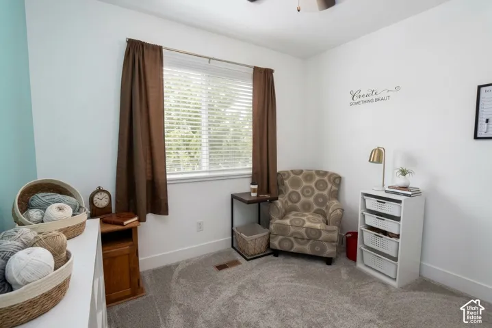 Carpeted room with a ceiling fan, a window with blinds, and a built-in wall shelf with storage baskets