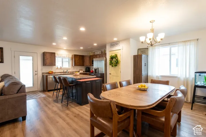 Open-concept space featuring wood-finish flooring, recessed lighting, a kitchen island with seating, dark wood cabinetry, and stainless steel appliances