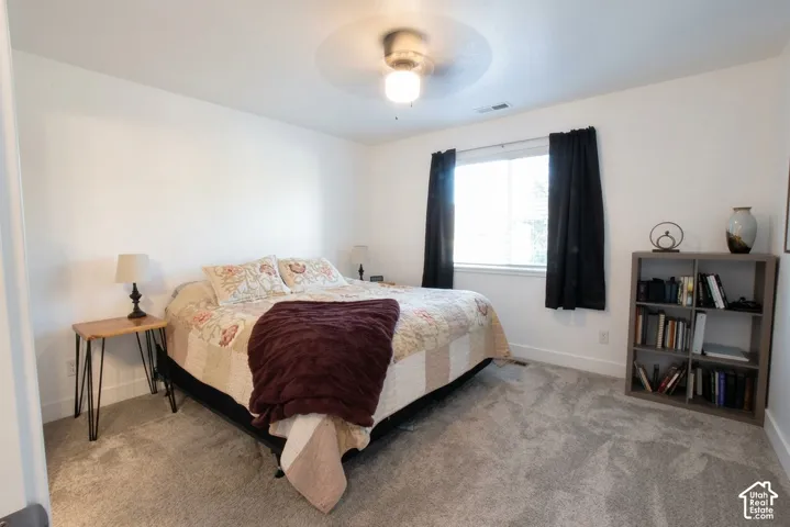 Neutral wall color, ceiling fan, window with blinds, and light gray carpet