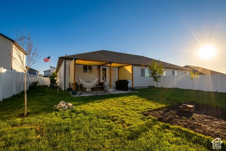 Expansive backyard featuring a covered patio, privacy fencing, and a manicured lawn